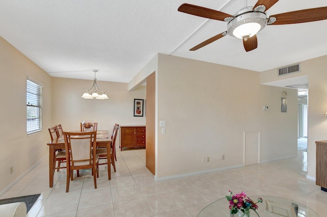 dining room featuring a textured ceiling, light tile patterned floors, and ceiling fan with notable chandelier