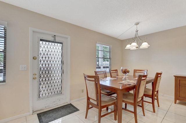 dining room featuring a textured ceiling, light tile patterned floors, and an inviting chandelier