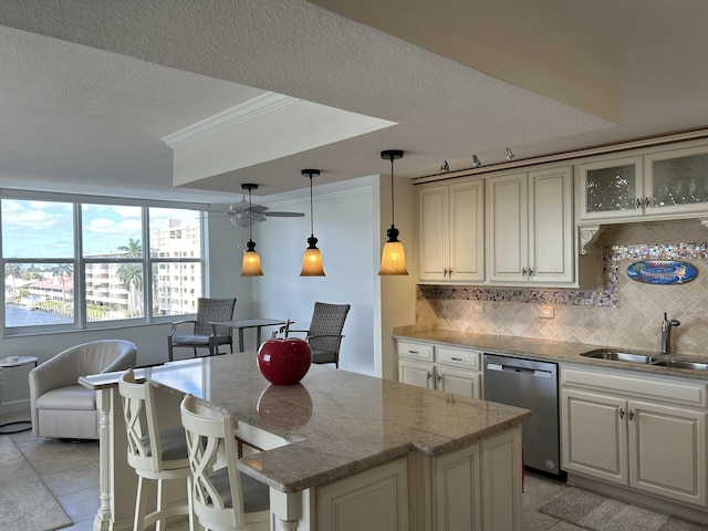 kitchen featuring decorative light fixtures, decorative backsplash, sink, light stone counters, and stainless steel dishwasher