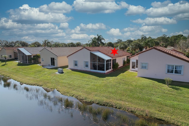 back of property with a sunroom, a lawn, and a water view