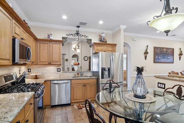 kitchen with light stone countertops, pendant lighting, stainless steel appliances, sink, and ornamental molding