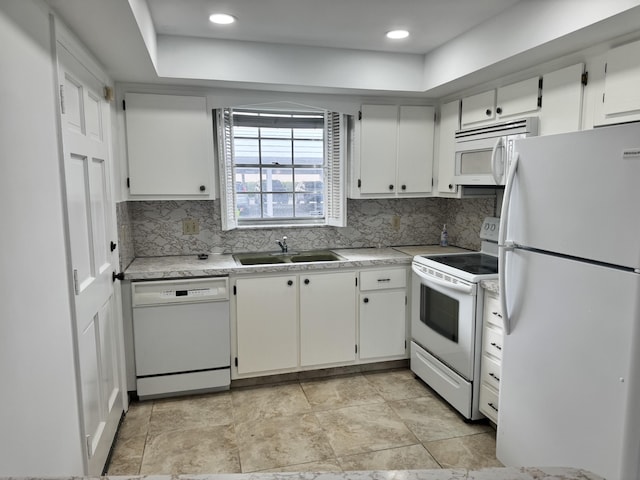 kitchen with tasteful backsplash, sink, white appliances, and white cabinetry