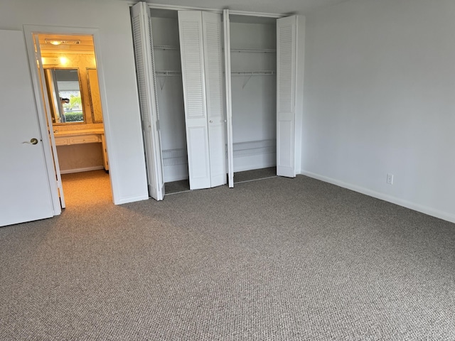 unfurnished bedroom with multiple closets and dark colored carpet