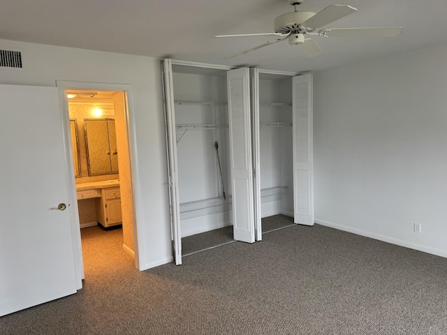 unfurnished bedroom with ceiling fan and dark colored carpet