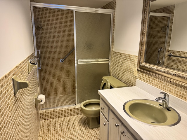 bathroom with toilet, a shower with door, tile walls, tile patterned floors, and vanity