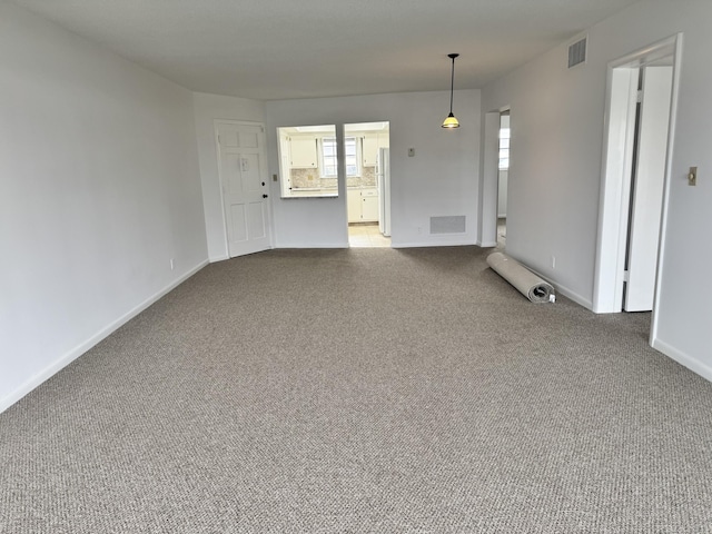 unfurnished living room featuring light colored carpet and plenty of natural light