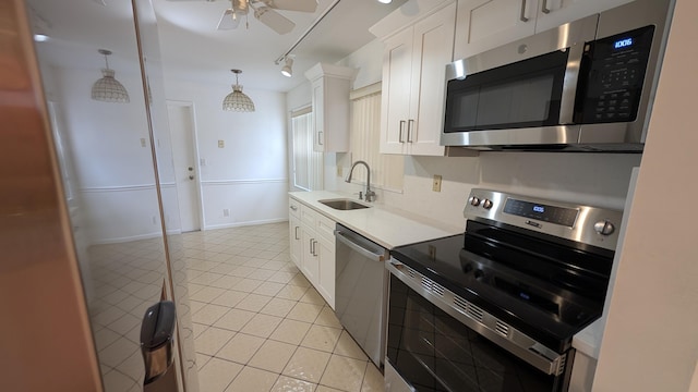 kitchen featuring light tile patterned floors, appliances with stainless steel finishes, pendant lighting, white cabinets, and sink