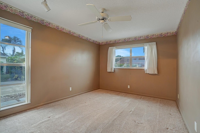 carpeted spare room featuring a textured ceiling and ceiling fan