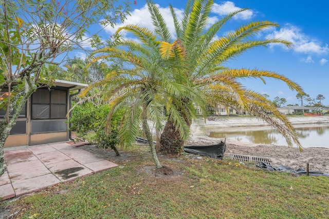 view of yard featuring a sunroom and a water view