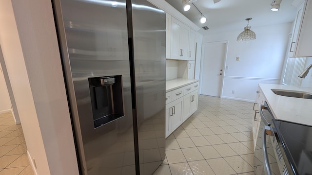 kitchen featuring white cabinets, decorative light fixtures, sink, stainless steel fridge, and light tile patterned floors