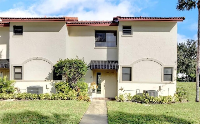 view of front of home with cooling unit and a front lawn