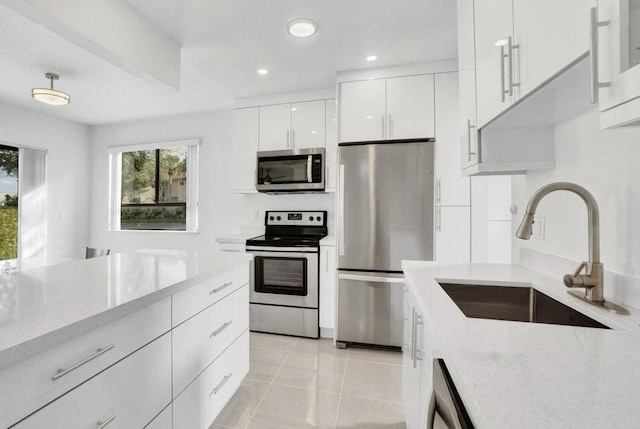 kitchen with sink, light tile patterned floors, stainless steel appliances, light stone counters, and white cabinets