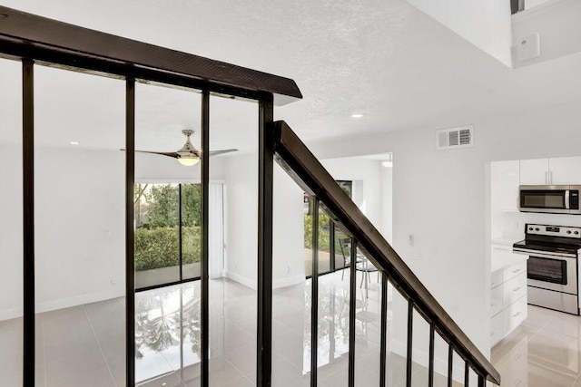 stairs with ceiling fan, tile patterned flooring, and a textured ceiling