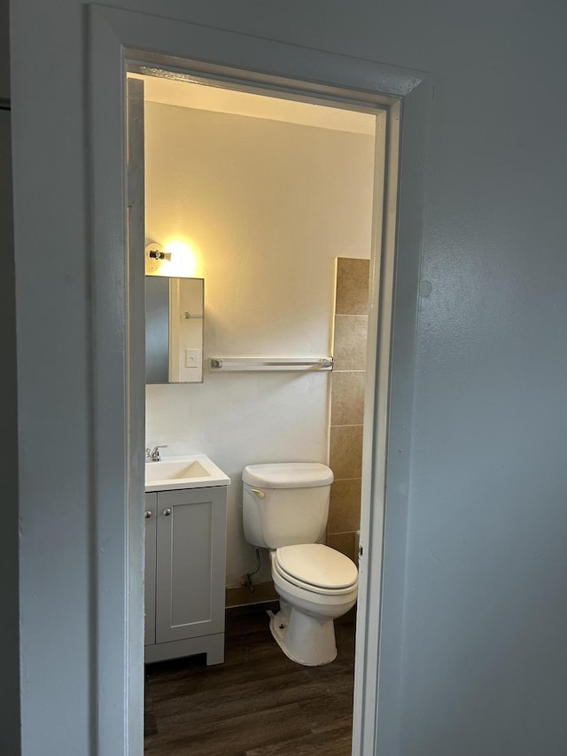 bathroom with toilet, vanity, and wood-type flooring