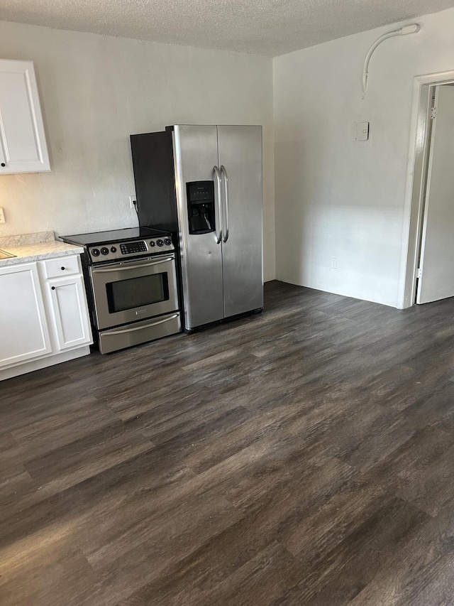 kitchen featuring a textured ceiling, dark wood-type flooring, stainless steel appliances, and white cabinetry