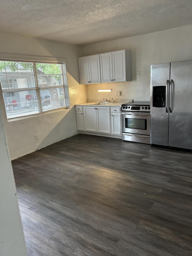 kitchen with a textured ceiling, white cabinets, dark hardwood / wood-style floors, and stainless steel appliances