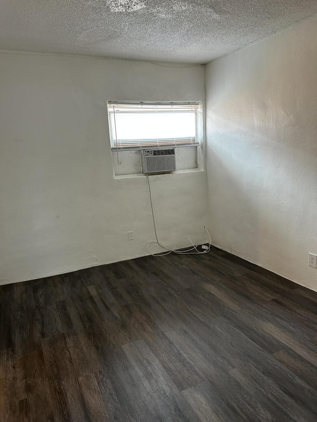 spare room featuring a textured ceiling, dark wood-type flooring, and cooling unit