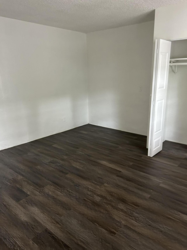 unfurnished bedroom featuring a textured ceiling, a closet, and dark hardwood / wood-style floors