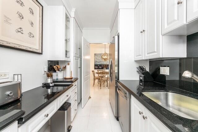 kitchen featuring sink, white cabinetry, ornamental molding, stainless steel appliances, and light tile patterned floors