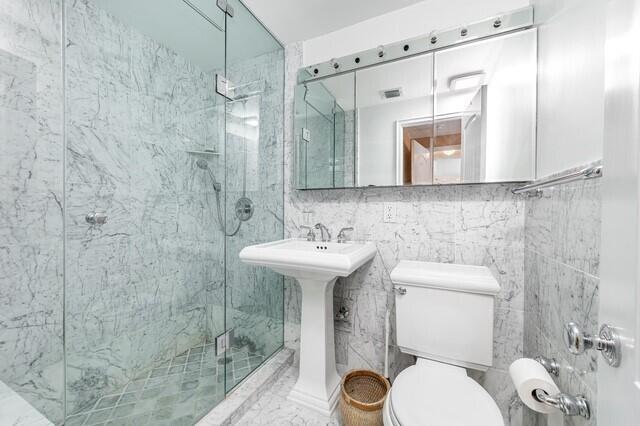 bathroom featuring toilet, tile walls, and an enclosed shower