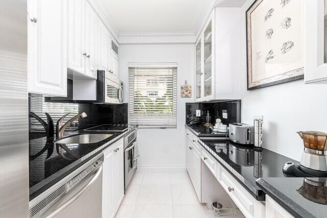 kitchen featuring white cabinets, appliances with stainless steel finishes, sink, ornamental molding, and light tile patterned flooring