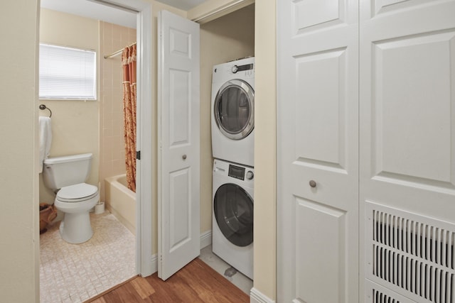 clothes washing area featuring stacked washer and dryer and light hardwood / wood-style flooring