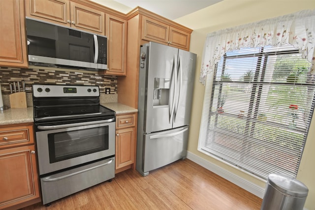 kitchen with backsplash, light hardwood / wood-style flooring, and stainless steel appliances