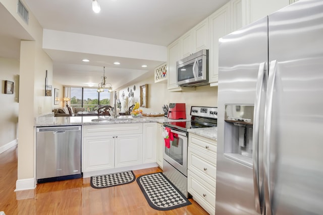 kitchen with kitchen peninsula, appliances with stainless steel finishes, white cabinets, and sink