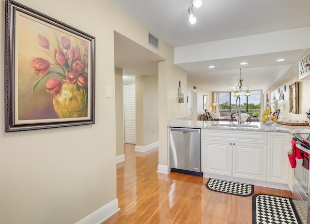 kitchen with stainless steel appliances, white cabinetry, light stone counters, and sink