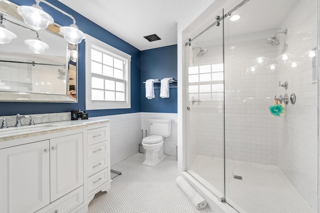 bathroom featuring tile patterned flooring, vanity, tile walls, toilet, and walk in shower