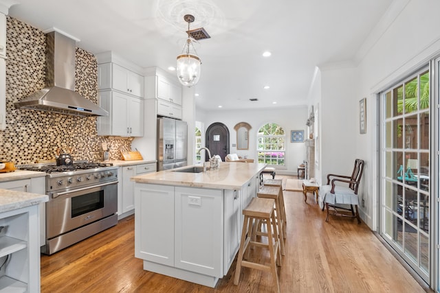 kitchen featuring white cabinets, sink, wall chimney range hood, and stainless steel appliances