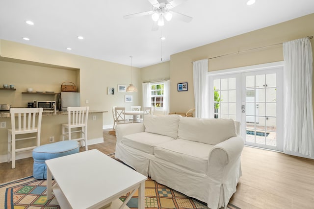 living room with ceiling fan, light hardwood / wood-style flooring, and french doors