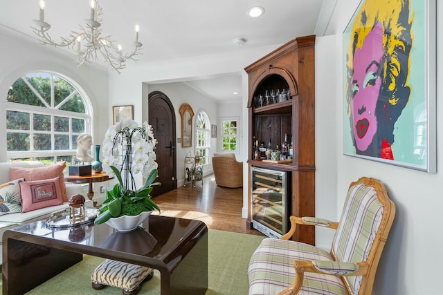 sitting room with ornamental molding, a healthy amount of sunlight, wine cooler, and wood-type flooring