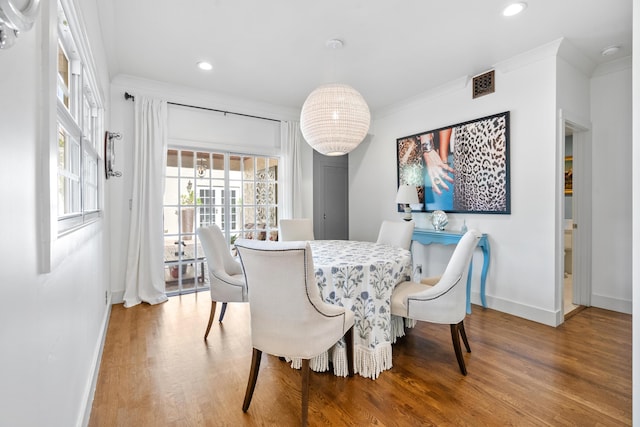 dining area with ornamental molding and hardwood / wood-style floors