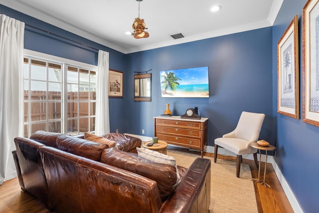 living room with an inviting chandelier, ornamental molding, and light hardwood / wood-style floors