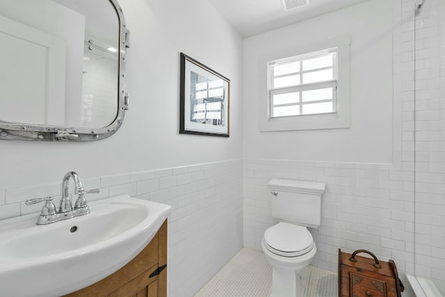 bathroom with toilet, tile walls, tile patterned floors, and vanity