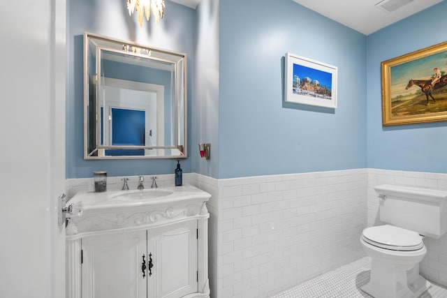 bathroom with tile walls, toilet, vanity, and tile patterned flooring