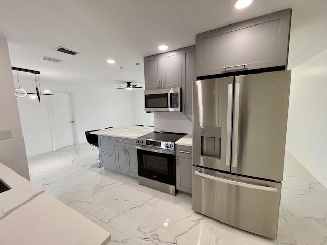 kitchen with ceiling fan, hanging light fixtures, appliances with stainless steel finishes, and gray cabinets