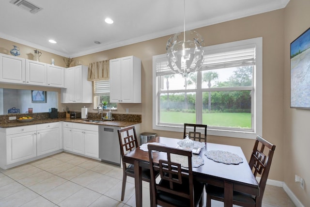 kitchen with stainless steel dishwasher, sink, light tile patterned flooring, hanging light fixtures, and white cabinets