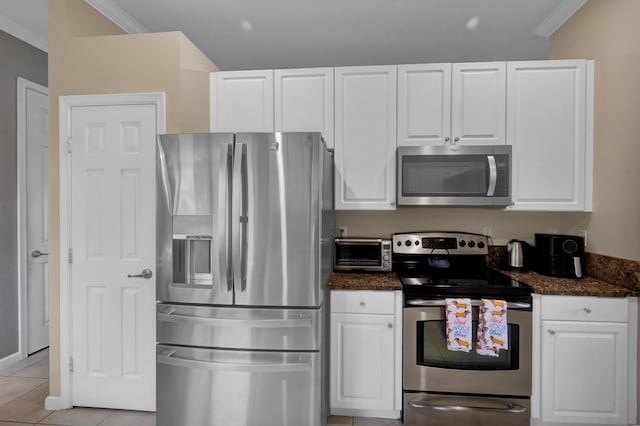 kitchen with light tile patterned floors, stainless steel appliances, dark stone countertops, and white cabinets