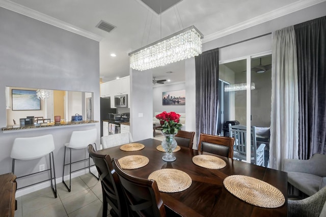 tiled dining room featuring a chandelier and ornamental molding