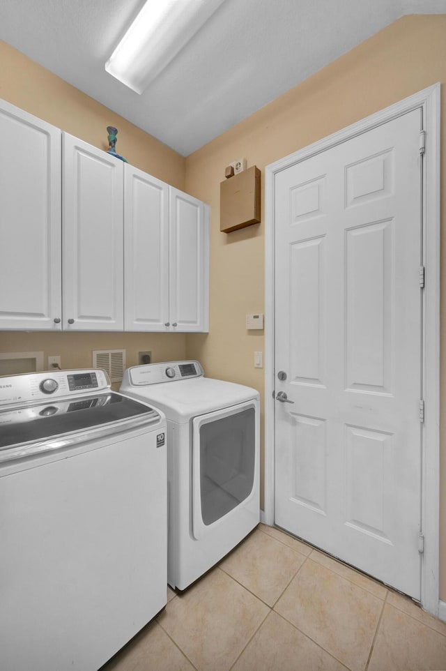 laundry area with light tile patterned flooring, independent washer and dryer, and cabinets