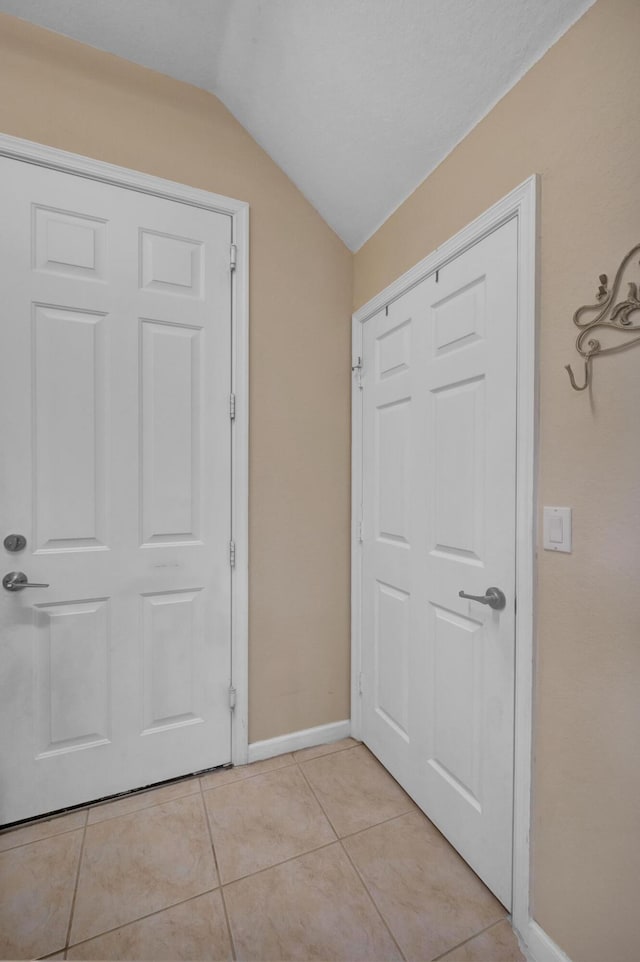 interior space featuring light tile patterned floors and vaulted ceiling