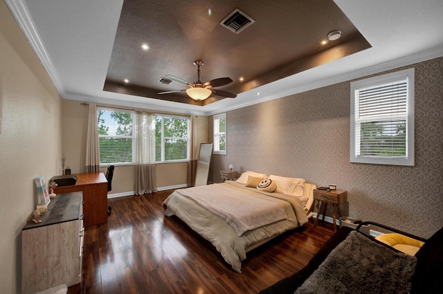 bedroom featuring dark wood-type flooring, ceiling fan, crown molding, and a tray ceiling