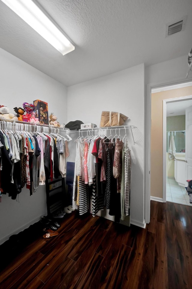 walk in closet with dark wood-type flooring