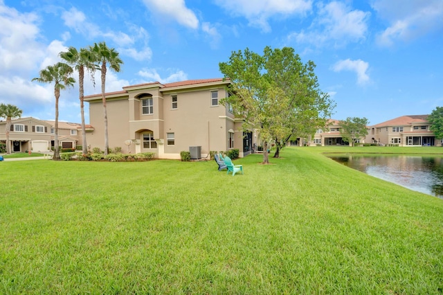 back of property featuring a lawn, a water view, and central AC