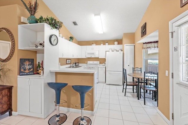 kitchen with kitchen peninsula, a breakfast bar area, white appliances, lofted ceiling, and white cabinets