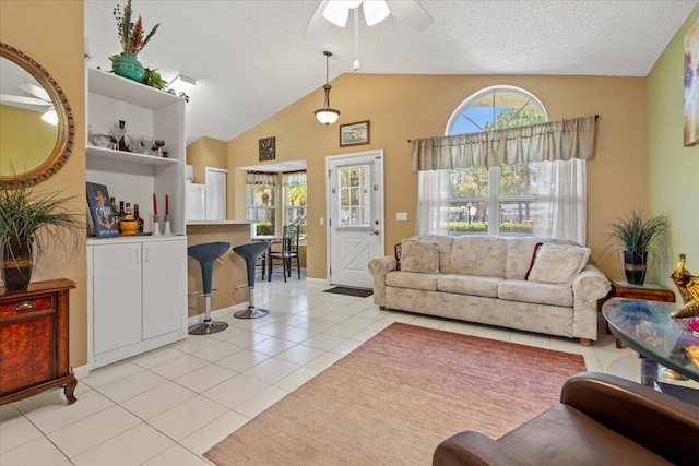 living room with ceiling fan, a textured ceiling, lofted ceiling, and light tile patterned flooring