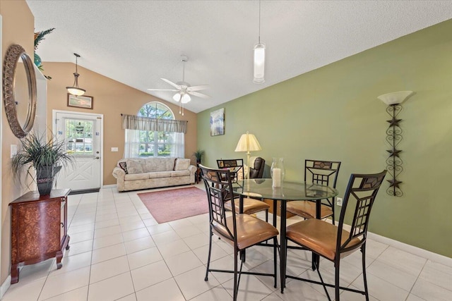 tiled dining room featuring a textured ceiling, ceiling fan, and lofted ceiling