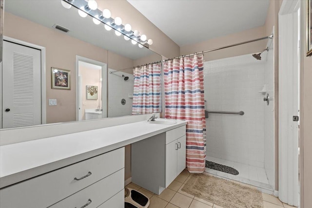 bathroom with visible vents, tile patterned flooring, tiled shower, and vanity